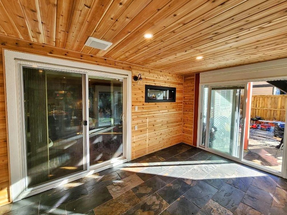 Empty room with a stone tile floor, wooden walls, and a sliding glass door.