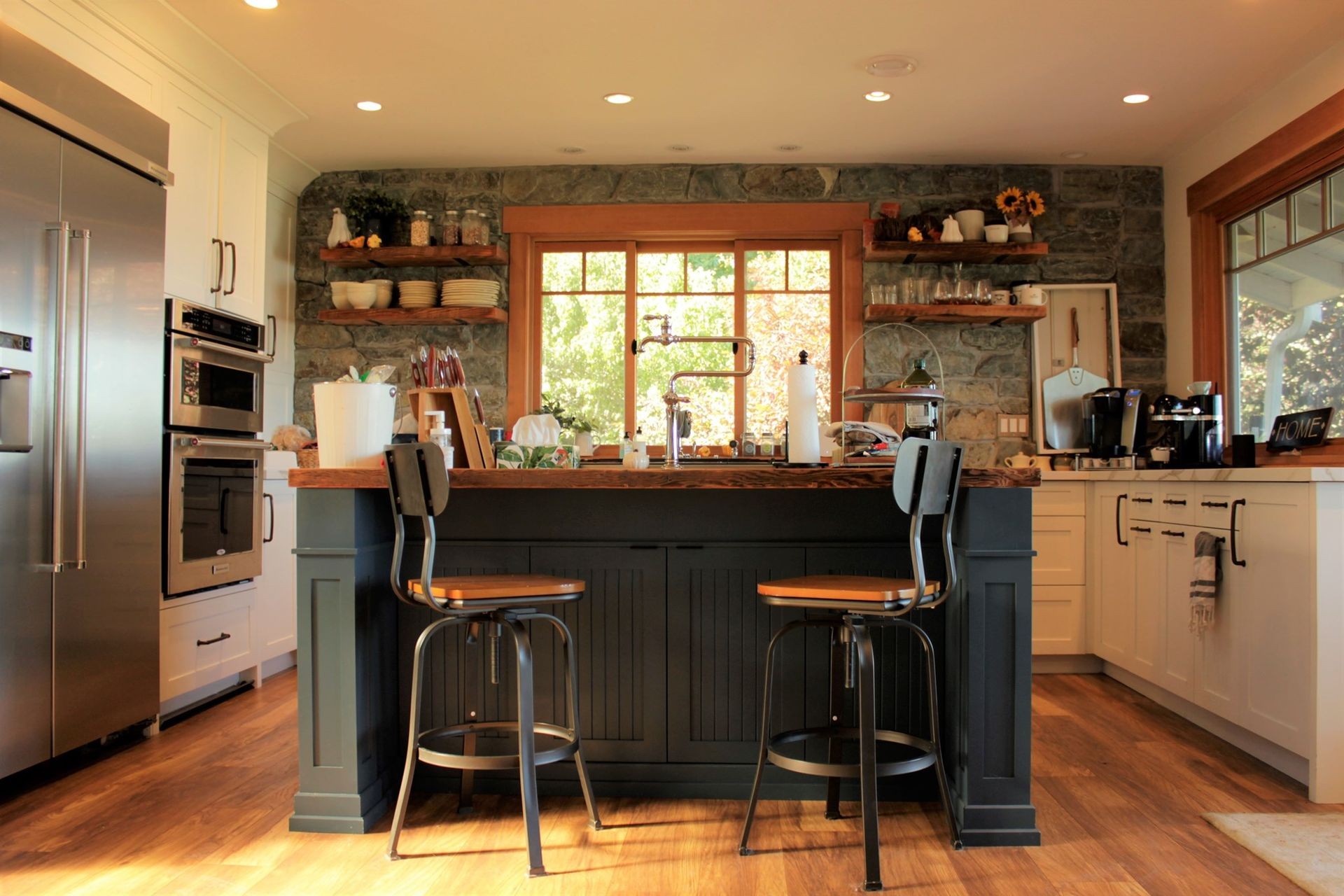 Mixed-material kitchen with wood floors and a black kitchen island.